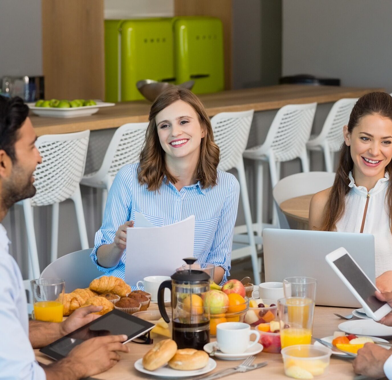 Business colleagues discussing over digital tablet while having breakfast
